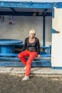 happy attractive senior woman at an old abandoned busstop