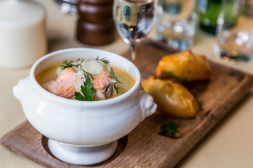 Restourant serving dish - salmon soup on wooden board with pie,
