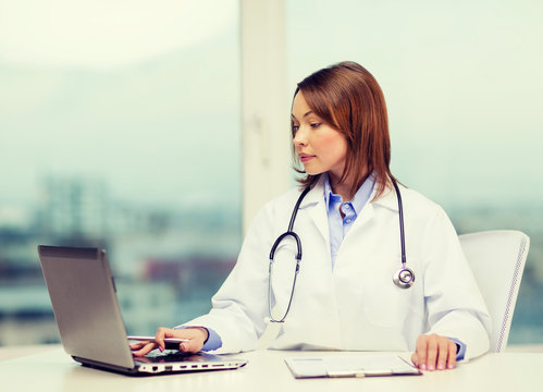 Busy Doctor With Laptop Computer And Clipboard