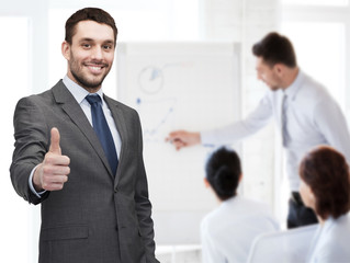 Fototapeta premium handsome buisnessman showing thumbs up in office