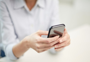 close up of woman texting on smartphone at office