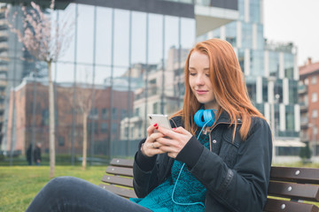 Beautiful girl texting on a bench
