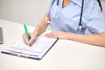 close up of female doctor writing prescription