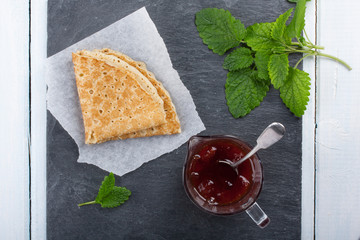 Pancake with jam and sprig of mint.
