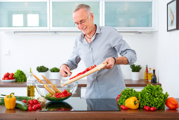 Mature man in the kitchen prepare salad IX