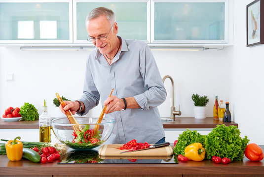 Mature man in the kitchen prepare salad V