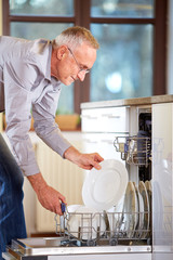 Senior man empty out the full dishwasher