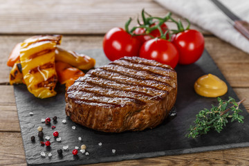 grilled beef steak with vegetables on a wooden surface