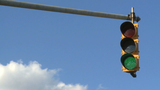 A set of traffics lights against a bright blue sky.