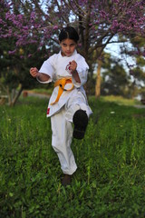 Young girl in kimono w yellow belt exercising karate.