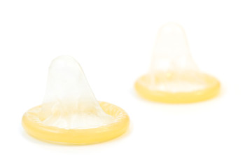 Closeup of two rolled-up condoms, isolated on white background