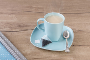 Cup of tea with milk on woden table