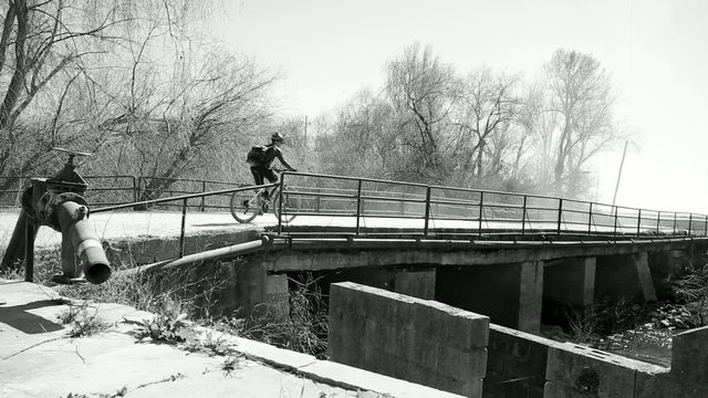 monochrome mountain bicycle riding on a bridge in a foggy day