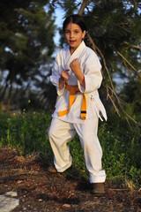 Young girl in kimono w yellow belt exercising karate.