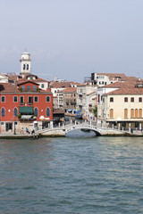 Fototapeta na wymiar Quay and pedestrian bridge over channel in Venice