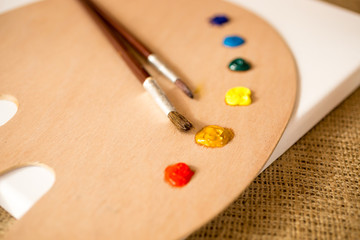 Obraz na płótnie Canvas Closeup shot of wooden pallet, brushes and oil paint blobs