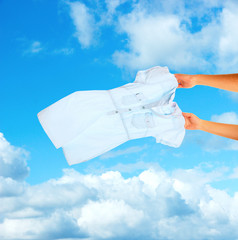 Fototapeta premium Hands holding flying shirt on sky background