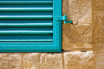 Window blue closed shutters on a stone wall. Close up.