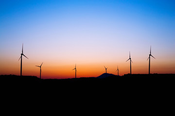 Wind farm silhouette in sunset light. Windmills.