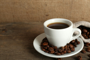 Cup of coffee with beans on rustic wooden background