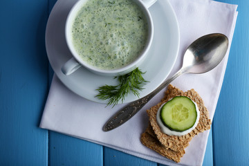 Cucumber soup in bowl on color wooden planks background