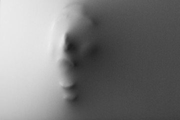 Screaming human face pressing through fabric as horror