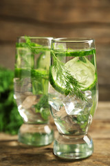 Glasses with fresh organic cucumber water on wooden table