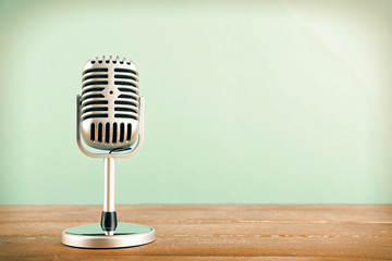 Retro microphone on wooden table on blue background
