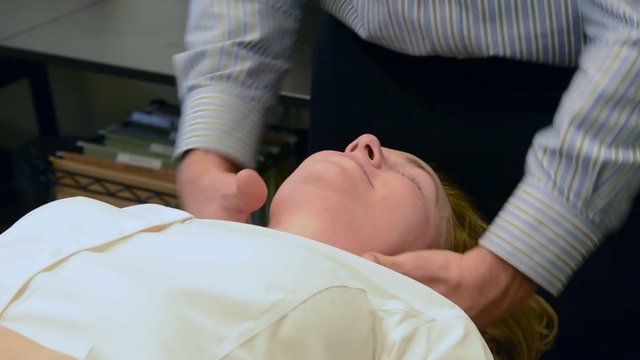 A woman receiving a neck adjustment in a chiropractic office