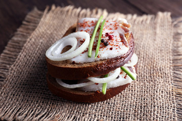 Sandwiches with lard and onion on sackcloth on table close up