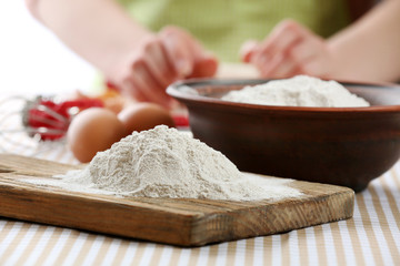 Young woman prepares dough on table close up