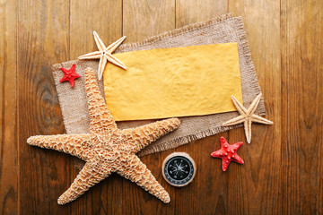 Fototapeta na wymiar Card blank with sea stars and compass on wooden background