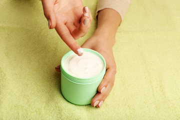 Female hands with jar of cream on fabric background