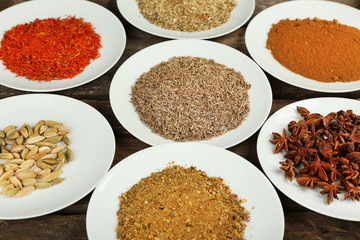 Different spices on plates, on old wooden table