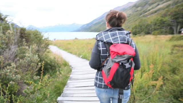 Woman with backpack walking towards Argentino Lake