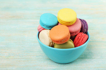 Tasty colorful macaroons on color wooden background