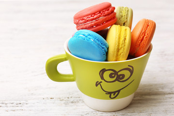 Cup of tasty colorful macaroons on color wooden background