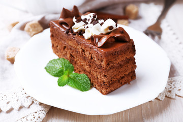Tasty piece of chocolate cake on wooden table background