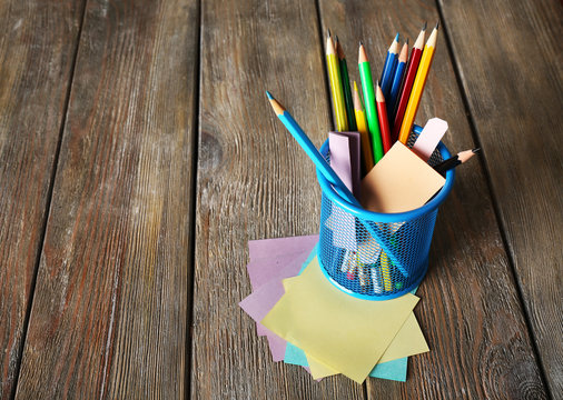 Colorful pencils in metal holder with sticky notes