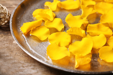 Rose petals in bowl on wooden background