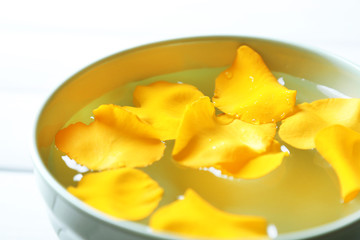 Rose petals in bowl on wooden background