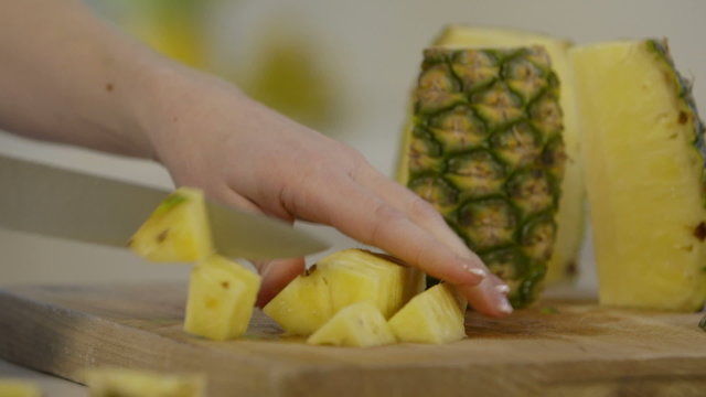 Close shot of woman cutting up pineapple chunks