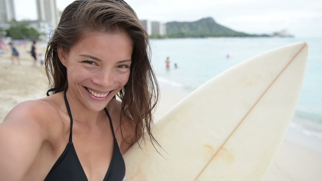 Surfing surfer girl taking selfie with surfboard on beach