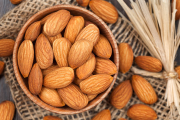 Almonds super foods in a wooden dish on vintage textile backgrou