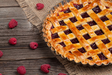Raspberry pie with fresh raspberries and jam on vintage wood