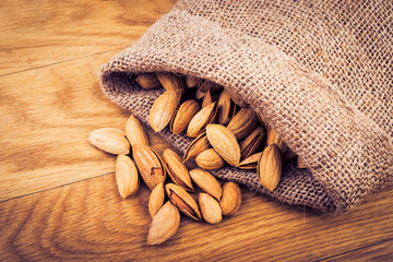 small sack bag with almonds on wooden table