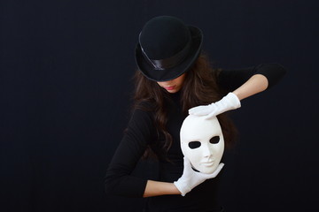 white theatrical mask in her hands.on a dark background