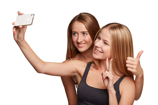 Two girls friends taking selfie with smartphone, isolated on whi