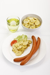 Wiener Würstchen mit Kartoffelsalat auf Teller, ein Glas Wasser