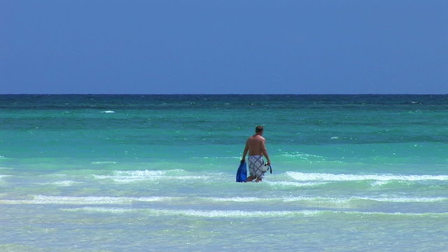 Man walks to sea on beautiful tropical beach